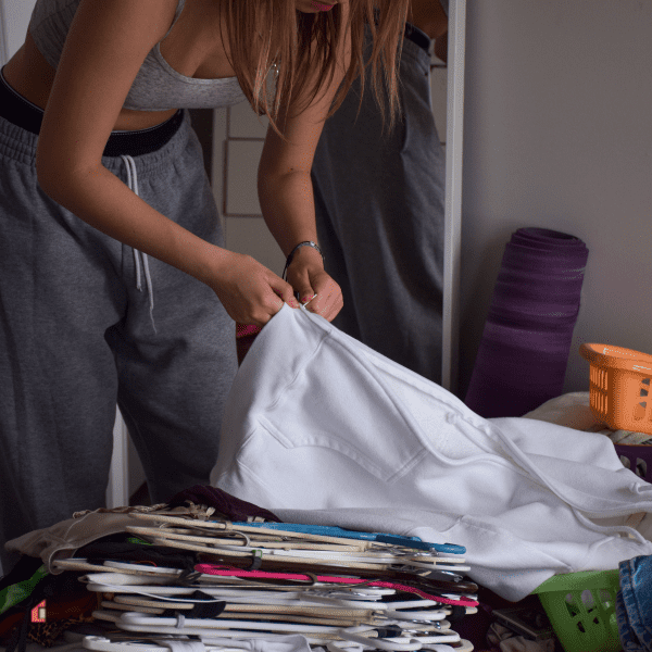 Young teenage girl cleaning and organizing her messy closet