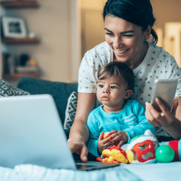 Modern stay at home mom with a baby using laptop at home.