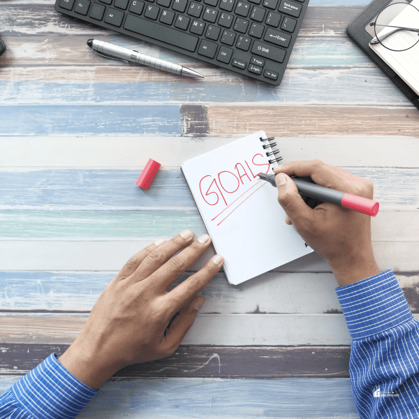 Young Man Writing New Year Goals on Notepad.