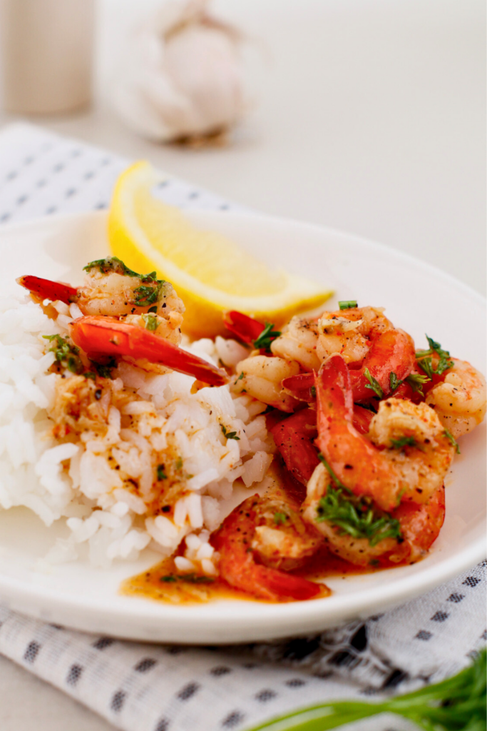 Puerto Rican garlic shrimp (camarones al ajillo) served over fluffy white rice with lemon wedge, sautéed shrimp in garlic butter white wine sauce with parsley and paprika, easy weeknight seafood dinner with Latin flavors.