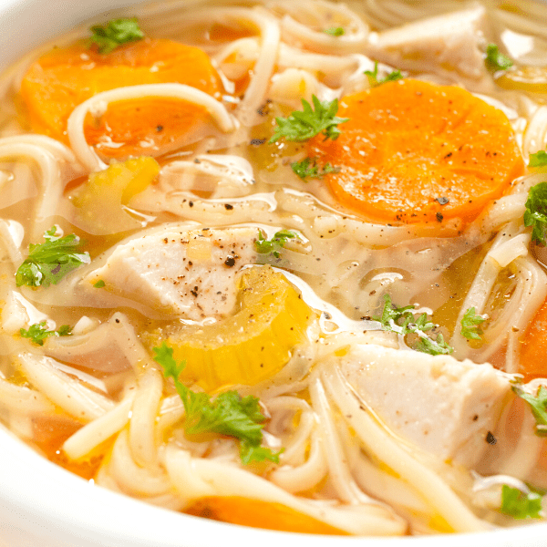 Chicken noodle soup on a plate orange background.
