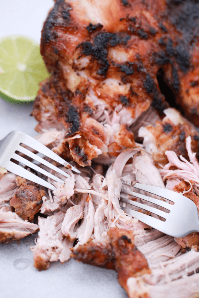 Pernil being shredded with two forks.