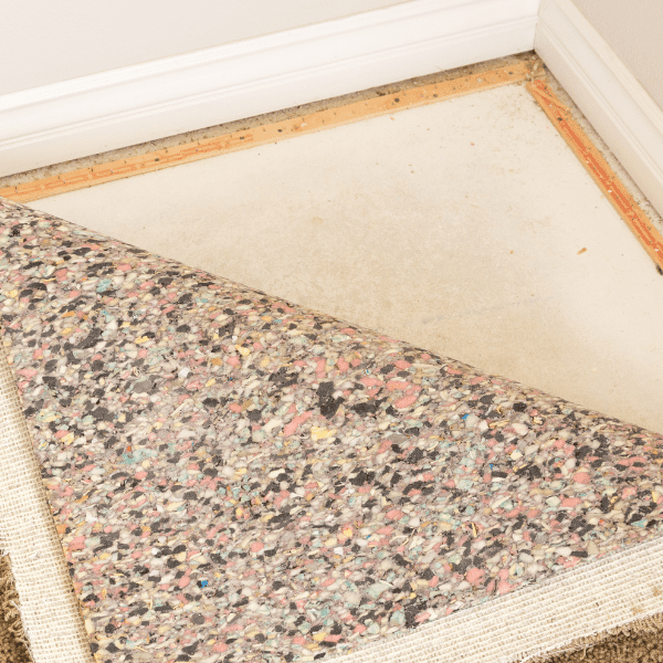 Pulled back carpet and padding showing yellowish stains.