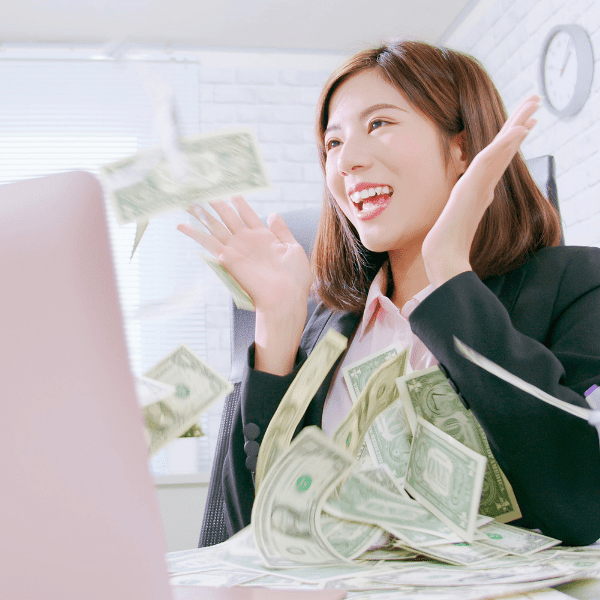 Woman sitting infront of her pink laptop and money  falling from the screen.