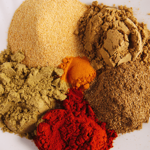 five dry seasonings on white background.