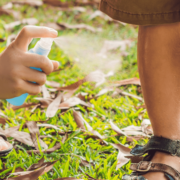 Mom spraying insect spray to her son.