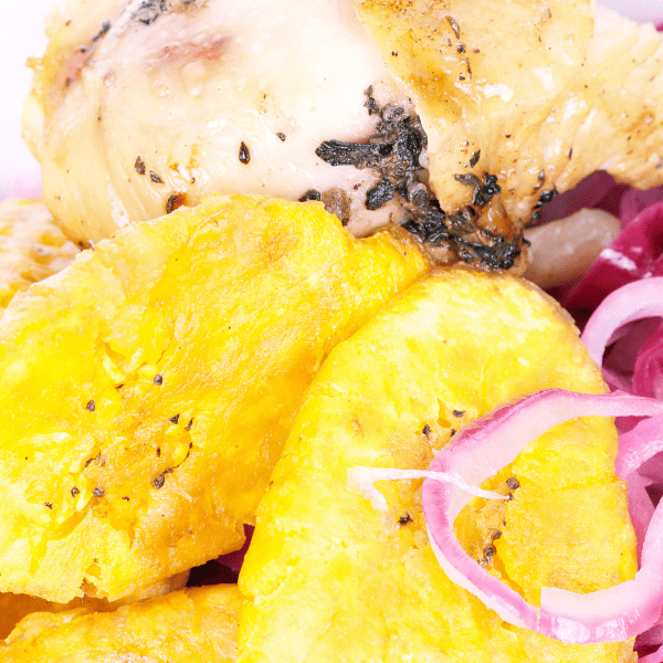 A closeup of Dominican food with picked root vegetable and chicken.