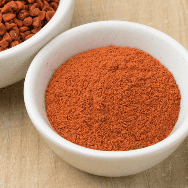 Bowl with dried Annatto seeds and a bowl with ground annatto powder close up.