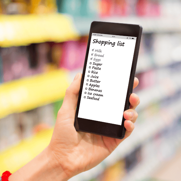 Closeup of a woman holding a phone and reading a shopping list.