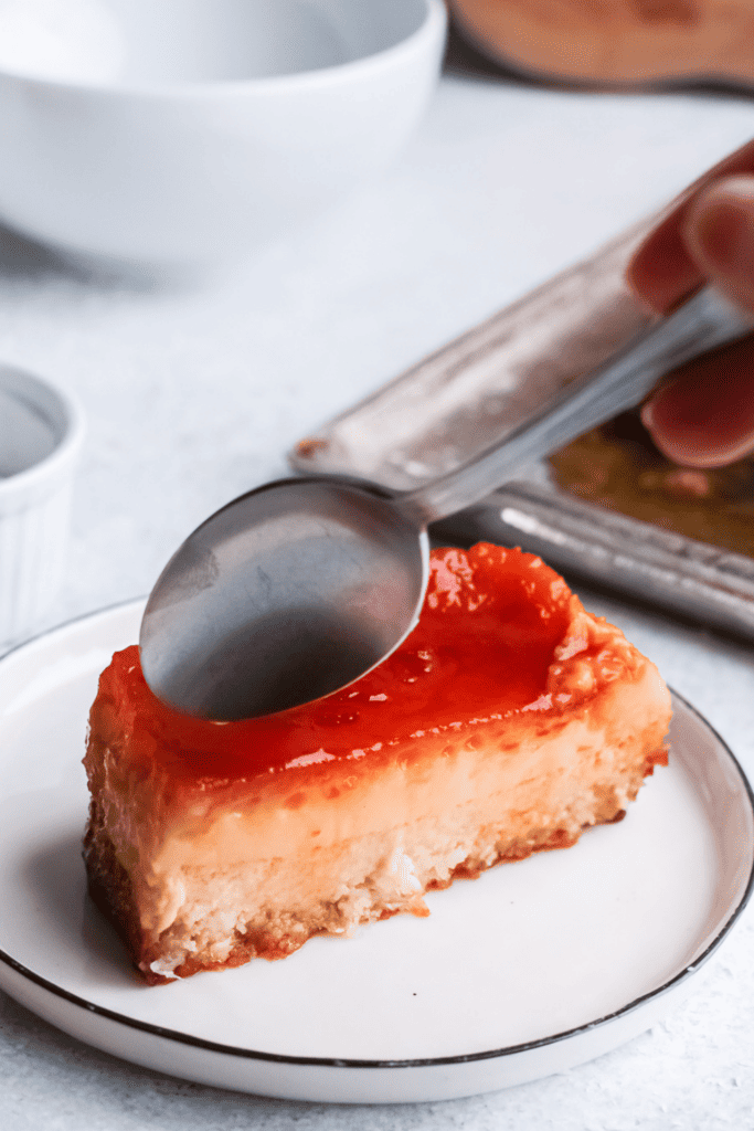 Closeup of piece of coconut flan (flan de coco) with a spoon on top.