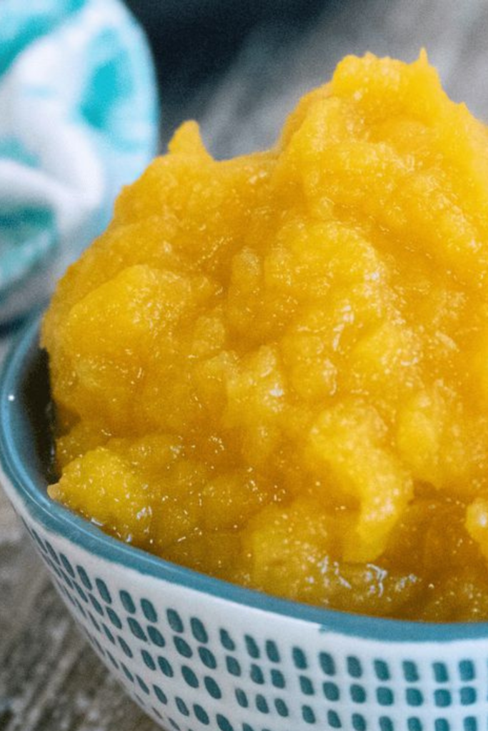Smooth, golden pumpkin puree served in a ceramic bowl on a wooden table.