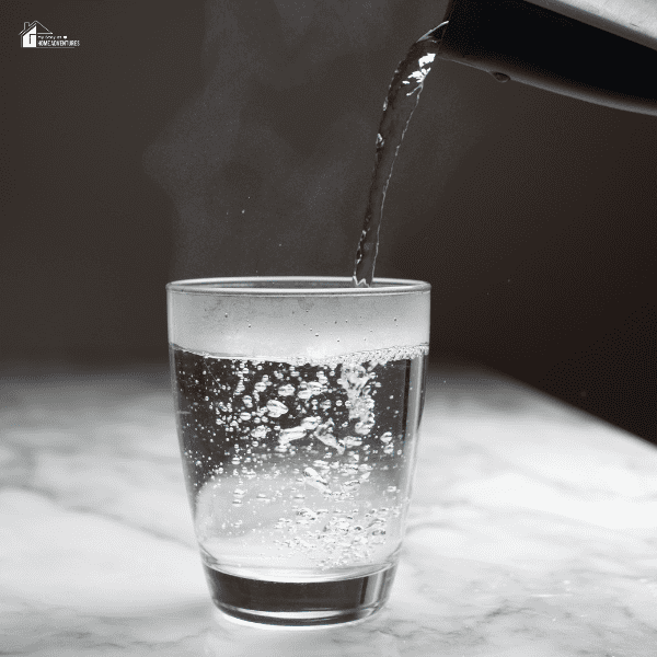 An image of a kettle pouring hot water over a glass cup.