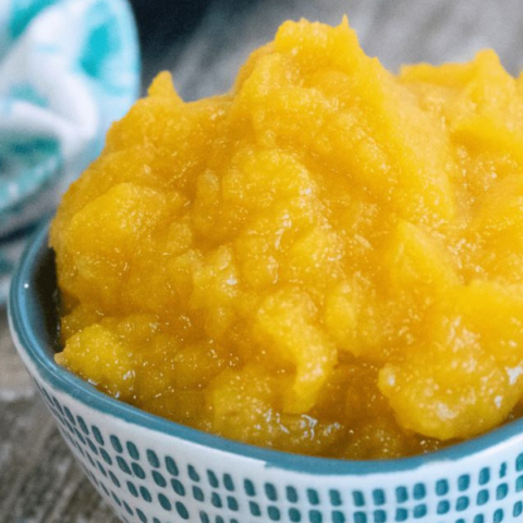Smooth, golden pumpkin puree served in a ceramic bowl on a wooden table.