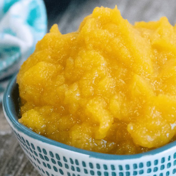 Smooth, golden pumpkin puree served in a ceramic bowl on a wooden table.