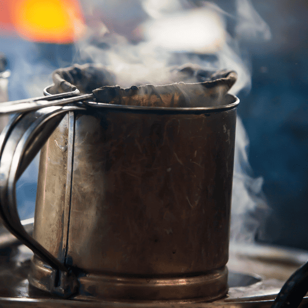 Cloth filter coffee and old stainless steal pot with steam coming out of it.