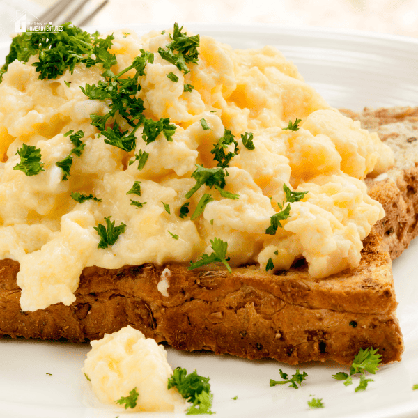 A close-up shot of creamy scrambled eggs on toast.