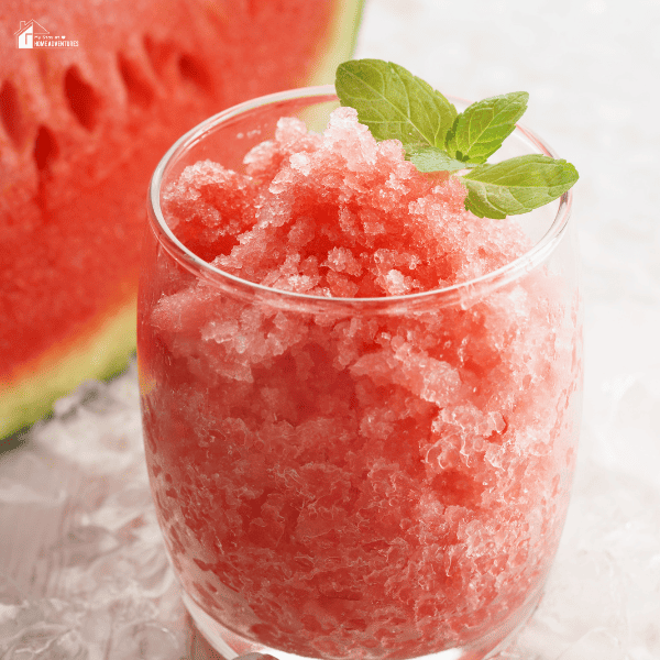 A close-up shot of a watermelon granita. Part of a watermelon is also included in the background.