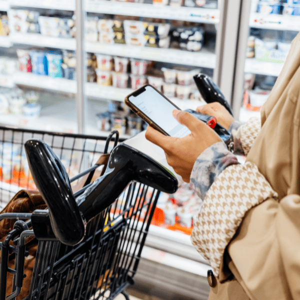 Woman using her smartphone to check her grocery lists while out shopping at a supermarket.