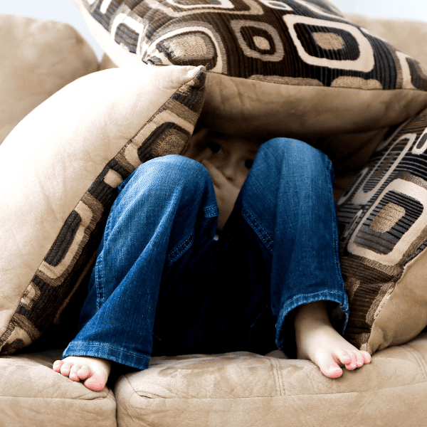 little boy hiding on the couch.