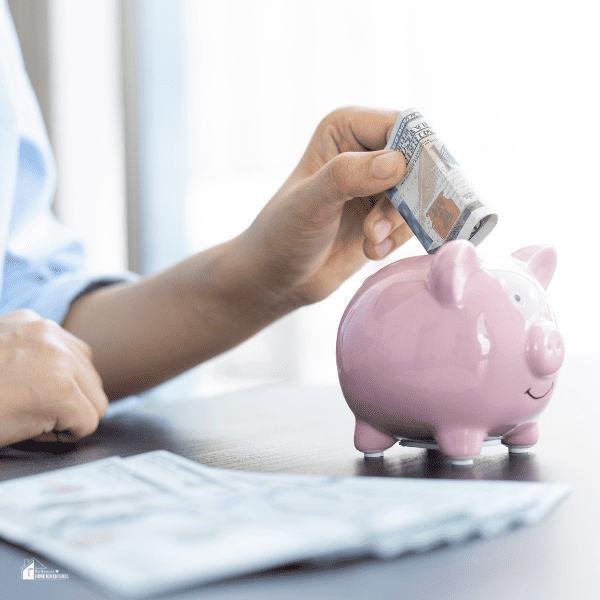 an image of someone putting money on a piggy bank