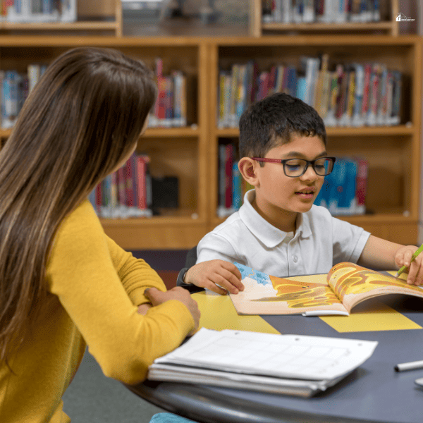 a boy being tutored by a lady in a library setting