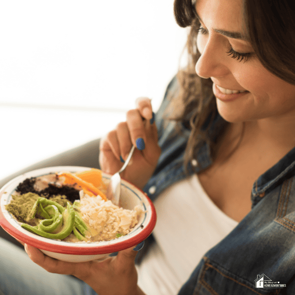 An image of a woman eating a bowl of oatmeal with add-ons.