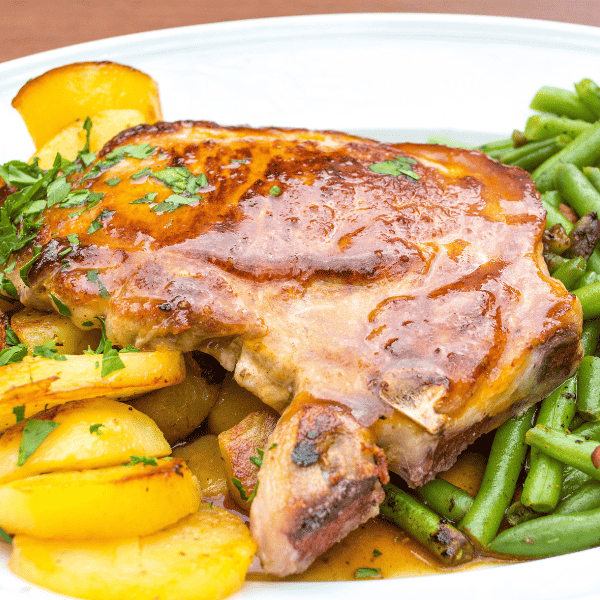 Baked pork chop with roasted potatoes, green beans and gravy.