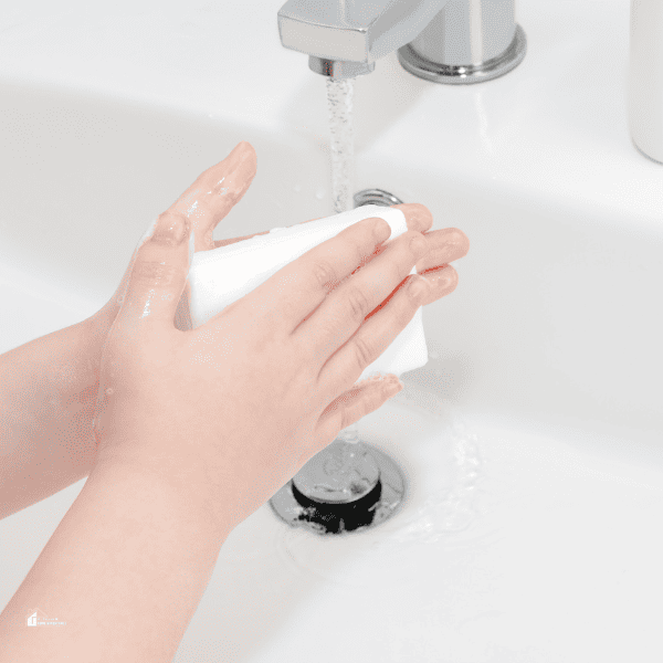 a kid washing her hand with bar soap