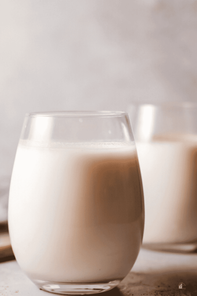 Close-up of a glass of Puerto Rican Coquito without eggs, topped with a light sprinkle of cinnamon, highlighting the creamy and frothy texture of this festive coconut-based drink.