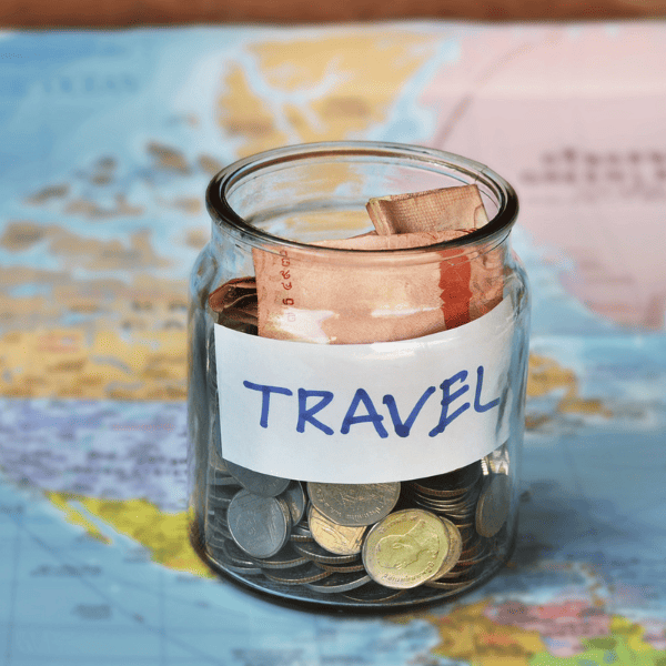 Travel budget vacation money savings in a glass jar on world map