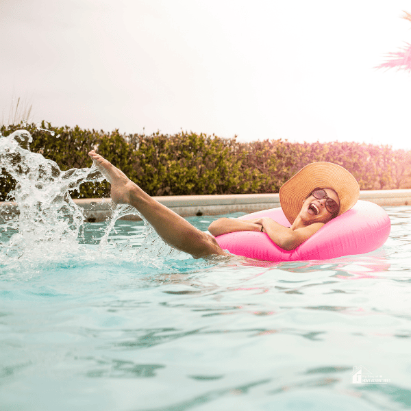 Young woman enjoying the summer weather in a swimming pool with a large inflatable