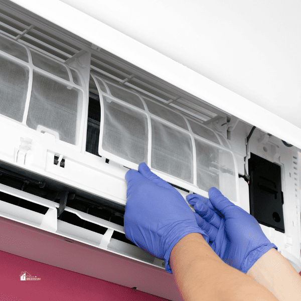 Person's Hands in Gloves cleaning the Air Conditioner Filter