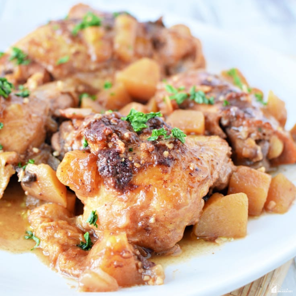 Instant Pot apple chicken thighs with tender chicken, cooked apples, savory sauce, and fresh herbs served on a white plate.