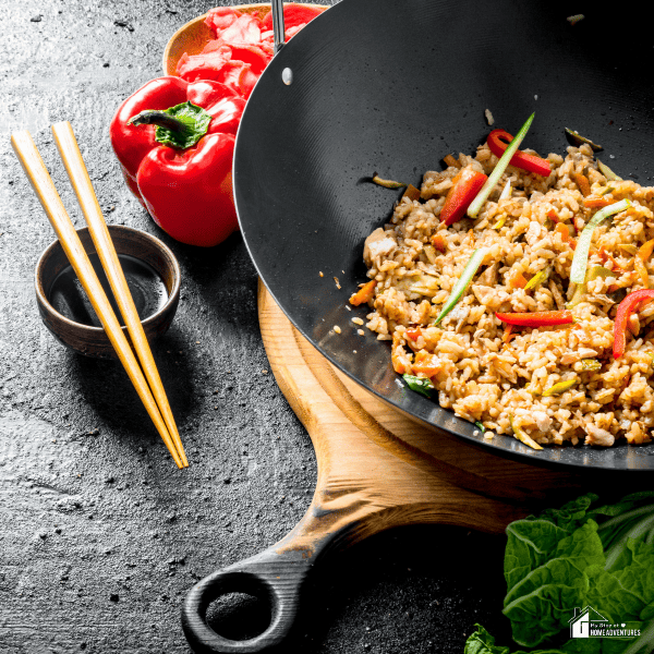 An image of a wok with fried rice, and chopsticks on the side.