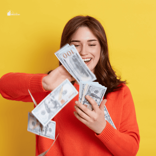 Dark Haired Female Wearing Casual Orange Jumper with Cash in Hands, Throwing Money, Isolated over Yellow Background.
