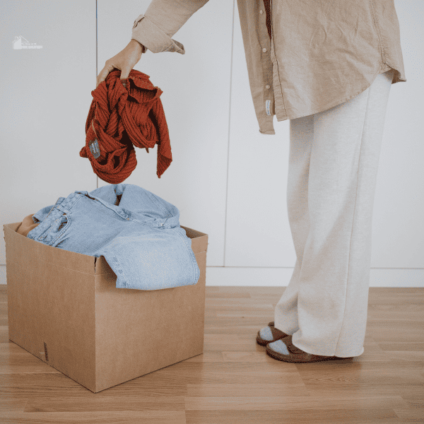 Person Putting Decluttered Clothes in a Box