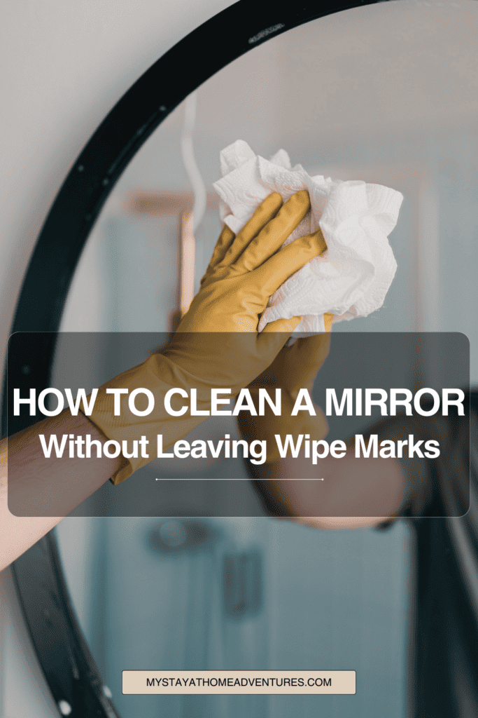 man cleaning mirror in bathroom with text: "How to Clean a Mirror Without Leaving Wipe Marks"