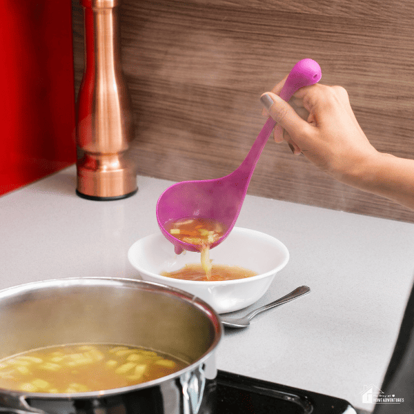 An image of a hand pouring hot soup in a white bowl.