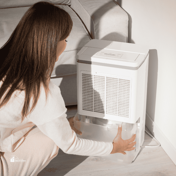 Woman changing water container in air dryer, dehumidifier, humidity indicator