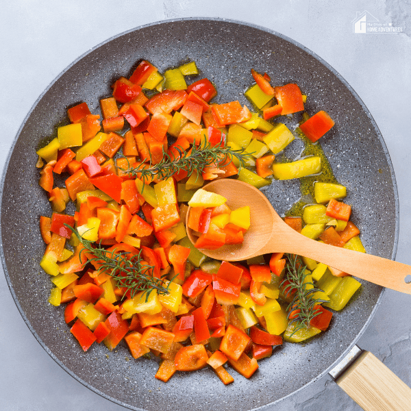 An image of bell peppers with thyme sprigs in a pan.