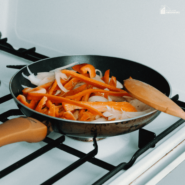 An image of onions and bell peppers cooked in a pan.