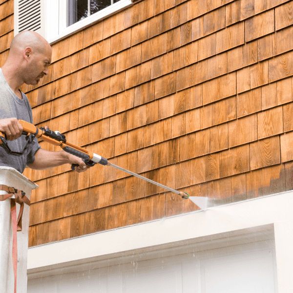 Close up of a man power washing exterior shingles