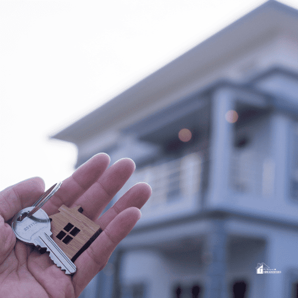 House Key in Hand with New House in the background