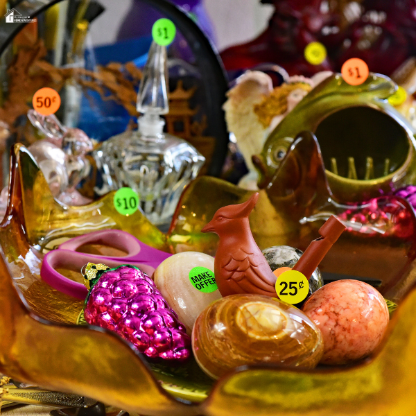 A close-up of assorted secondhand items with colorful price stickers displayed on a table at a yard sale.