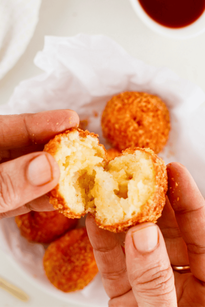 Puerto Rican bolitas de queso split open to show the warm cheesy center and crispy golden breadcrumb coating.
