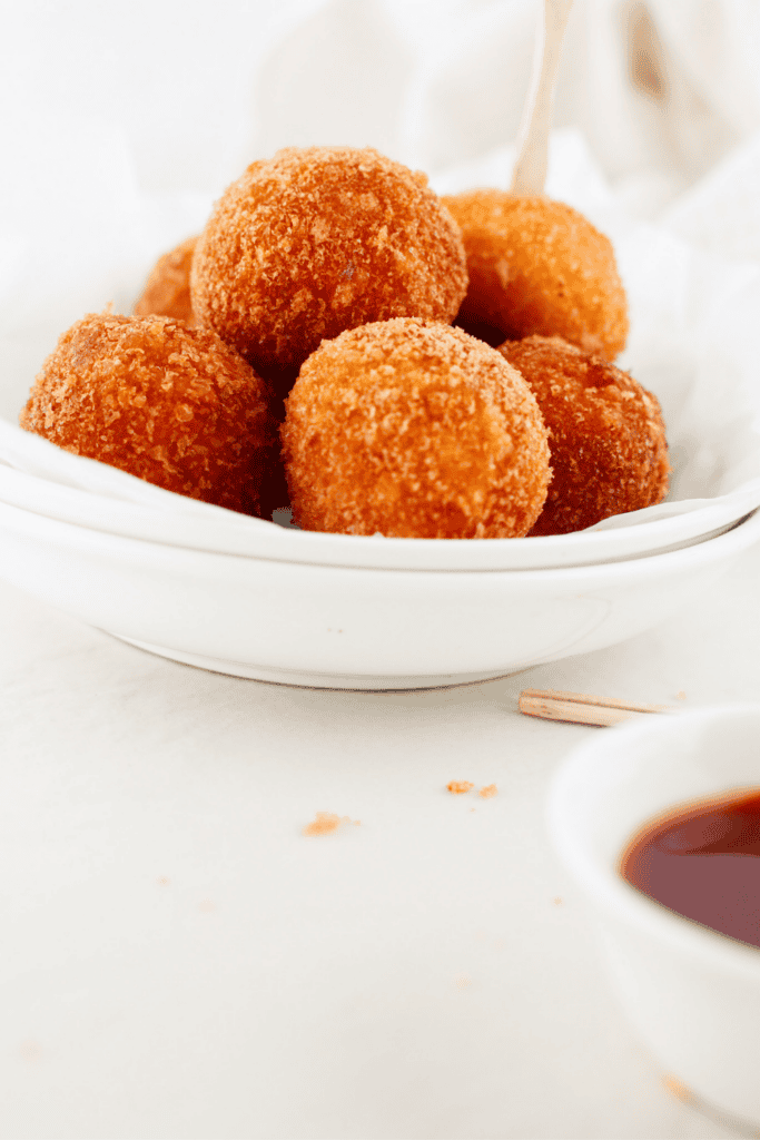 Crispy Puerto Rican fried cheese balls served with dipping sauce, golden brown on the outside and ready to enjoy.