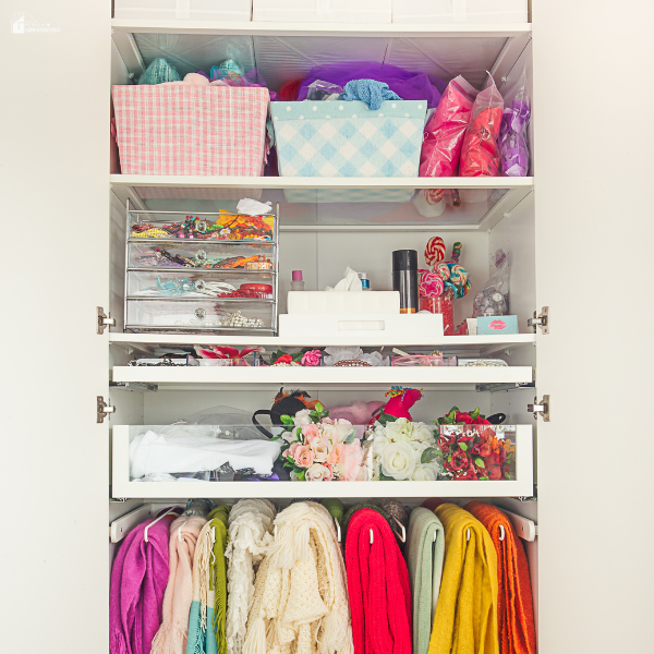 An organized bedroom closet filled with colorful storage bins, scarves, and accessories neatly arranged on shelves.