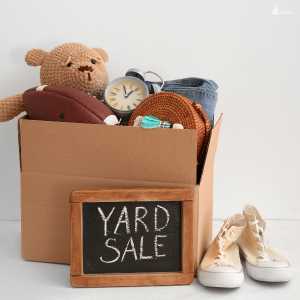 Box of popular yard sale items like toys, clocks, and clothes that are likely to sell well in 2026.