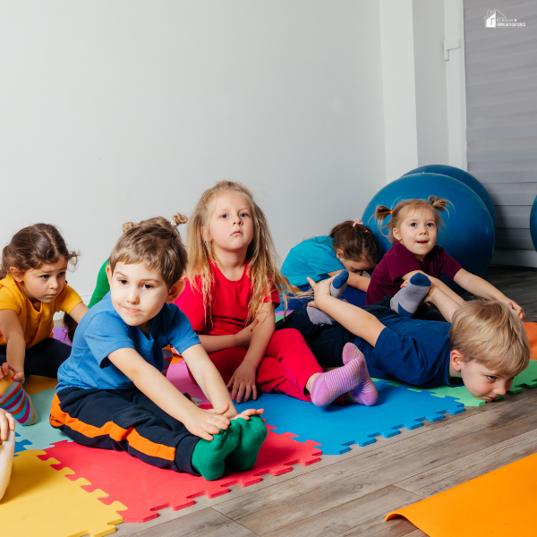 A group of kids stretches together on colorful foam mats indoors during a homeschool physical activity session.