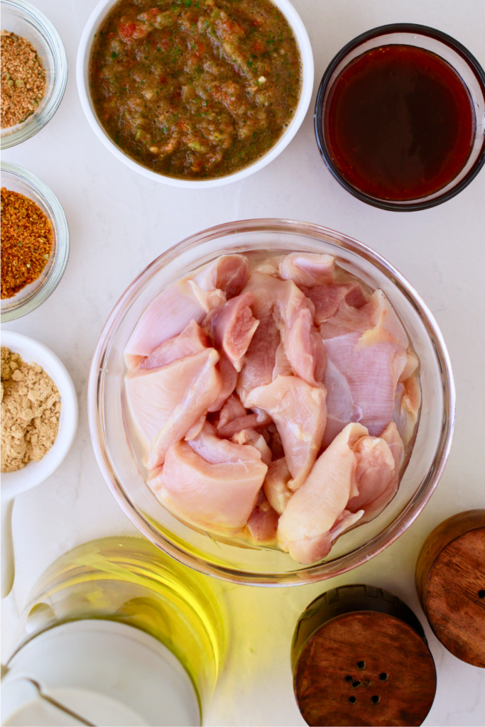Here’s an alt text description for the new image, optimized for Pinterest and screen readers:
Raw ingredients for Puerto Rican pinchos including chicken thighs, sofrito, BBQ sauce, sazón, adobo, garlic powder, oil, and seasoning displayed on a white surface.